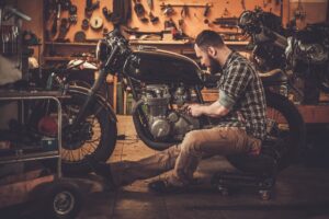 MECHANIC BUILDING VINTAGE STYLE CAFE RACER MOTORCYCLE IN CUSTOM GARAGE